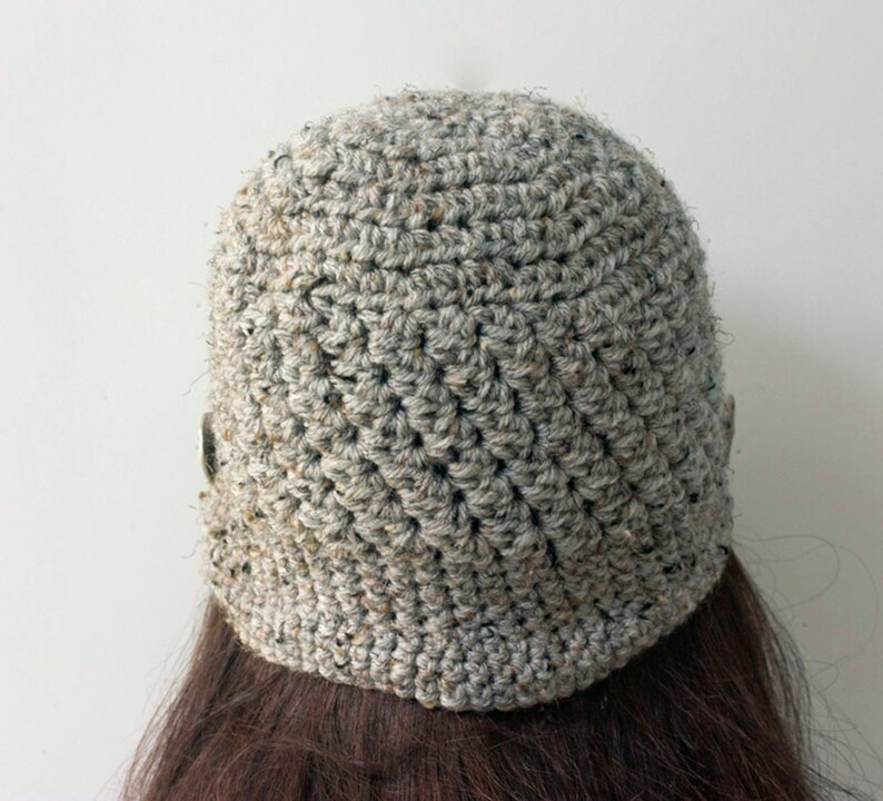 May include: A gray crocheted beanie hat with a textured pattern. The hat is made with a thick yarn and has a slouchy fit.