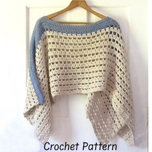 May include: A cream-colored, open-weave crochet poncho with a light blue neckline and sleeve accents. The poncho is displayed on a wooden hanger against a white door. The words "Crochet Pattern" are at the bottom.