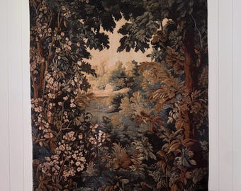 May include: A rectangular wall tapestry featuring a woven landscape scene with dark green trees, dense foliage, and light-colored flowering bushes. The central area depicts a distant, lighter-toned clearing with a soft, muted color palette of browns and greens.