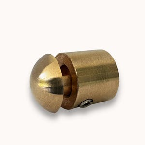 May include: A brass end cap for a glass rod or railing. The cap has a round, domed top and a threaded base.
