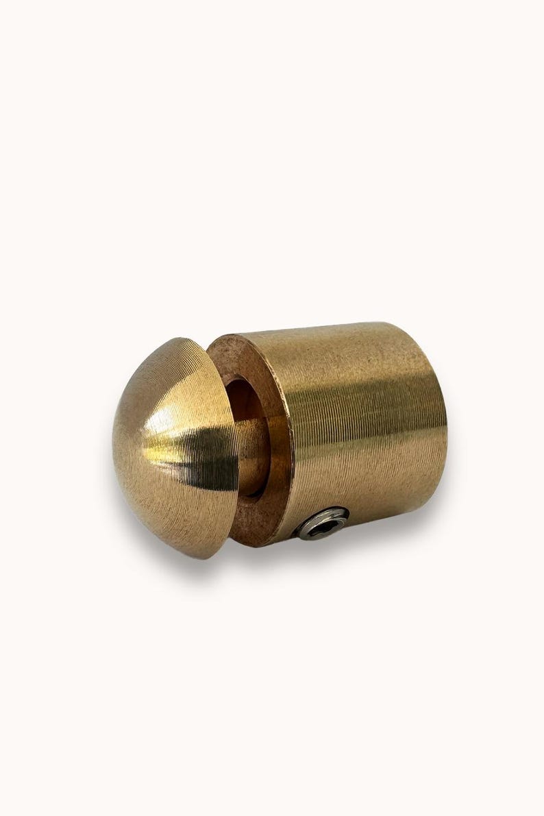 May include: A brass end cap for a glass rod or railing. The cap has a round, domed top and a threaded base.