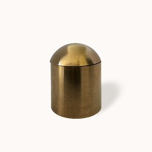 May include: A gold metal container with a domed lid. The container has a textured finish.