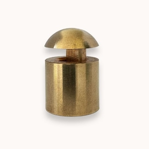 May include: A gold-toned metal bottle stopper with a dome-shaped top and a cylindrical base.