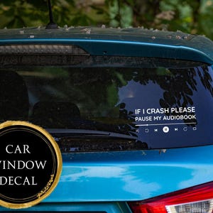 Può includere: Il lunotto posteriore di un'auto turchese mostra un adesivo bianco con il testo "IF I CRASH PLEASE PAUSE MY AUDIOBOOK" e icone di controllo multimediali. Un adesivo circolare nero e oro recita "CAR WINDOW DECAL".