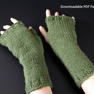 Könnte beinhalten: Ein Paar grüne gestrickte Fingerhandschuhe. Die Handschuhe sind mit einem einfachen Stichmuster gearbeitet und haben einen gerippten Bund. Downloadbarer PDF-Schnitt.