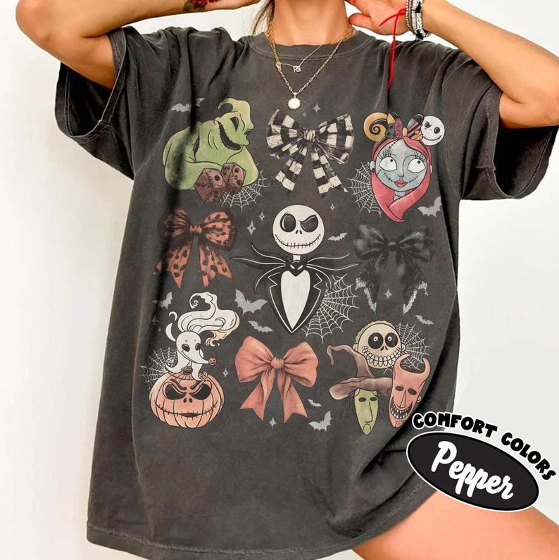 May include: A charcoal gray short-sleeve t-shirt featuring a graphic print of characters and bows from The Nightmare Before Christmas. The design includes Jack Skellington, Sally, Zero, Oogie Boogie, and Lock, Shock, and Barrel with spiderwebs.