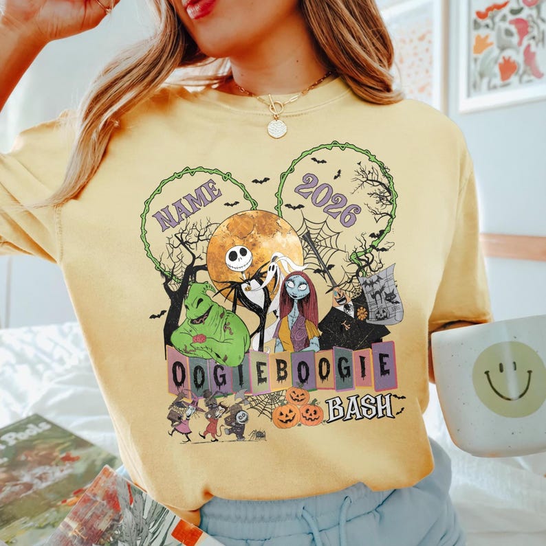 May include: A pale yellow t-shirt featuring a graphic print of characters from The Nightmare Before Christmas, including Jack Skellington, Sally, and Oogie Boogie. The design includes the text NAME, 2026, and OOGIE BOOGIE BASH with pumpkins.