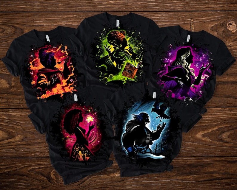 May include: Five black t-shirts with colorful graphic designs. Each shirt features a silhouette of a character surrounded by vibrant hues of orange, green, purple, pink, and blue. The designs appear to be inspired by fantasy or mystical themes.