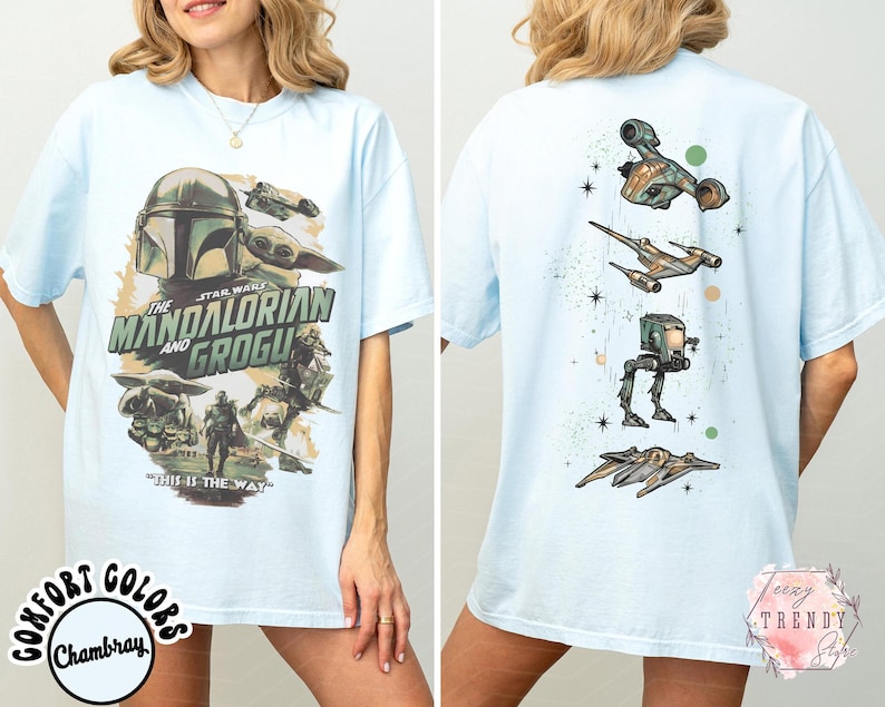 Pode incluir: Uma t-shirt azul claro com uma impress&atilde;o gr&aacute;fica de The Mandalorian e Grogu na frente, incluindo o texto "The Mandalorian and Grogu" e "This is the way". As costas da t-shirt exibem um alinhamento vertical de v&aacute;rios ve&iacute;culos Star Wars.