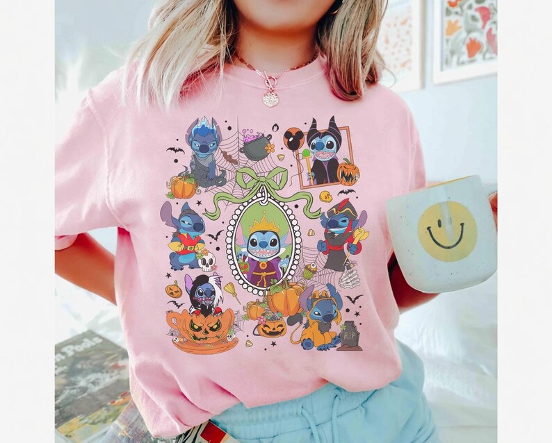 Może przedstawiać: Jasnor&oacute;żowa koszulka z halloweenową grafiką postaci z kresk&oacute;wek. Grafika zawiera dynie, nietoperze i postacie w kostiumach. W dłoni trzymany jest biały kubek z ż&oacute;łtą uśmiechniętą buzią.