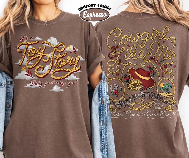 Może przedstawiać: Brązowy t-shirt z grafiką z przodu z napisem 'it's a Toy Story' wykonanym czcionką przypominającą linę wśr&oacute;d chmur oraz grafiką z tyłu z napisem 'Cowgirl like Me' i 'Takes One to Know One' z motywami kapelusza kowbojskiego i liny.