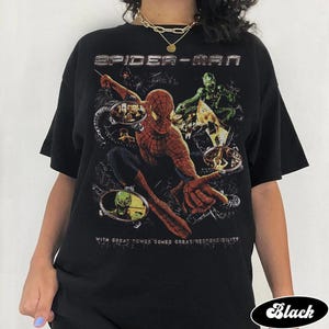 May include: Black Spider-Man t-shirt featuring a graphic of Spider-Man in action with the text "SPIDER-MAN" at the top. The shirt also includes the phrase "WITH GREAT POWER COMES GREAT RESPONSIBILITY".