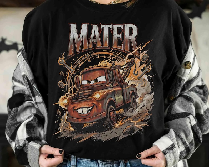 May include: Black t-shirt featuring a cartoon illustration of Mater from the movie Cars. The design includes the word "MATER" in large, distressed lettering above the character, with lightning bolts and tools surrounding the truck.