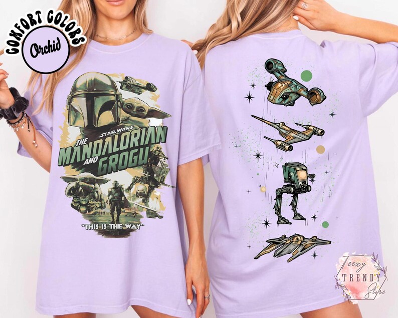 Pode incluir: Uma t-shirt roxo-claro com um gr&aacute;fico de The Mandalorian e Grogu na frente, incluindo o texto "The Mandalorian and Grogu" e "This is the way". As costas apresentam um alinhamento vertical de quatro naves espaciais e ve&iacute;culos Star Wars.