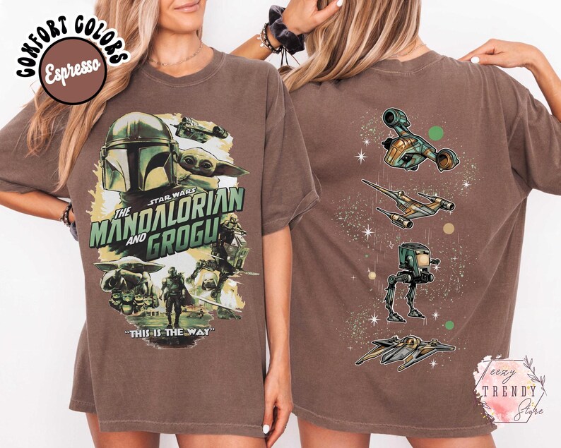 Pode incluir: Uma t-shirt cor de caf&eacute; expresso com um gr&aacute;fico frontal de The Mandalorian e Grogu com o texto "The Mandalorian and Grogu" e "This is the way". O gr&aacute;fico traseiro mostra quatro ve&iacute;culos de Star Wars e detalhes de estrelas na vertical.