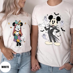 May include: White t-shirts featuring Halloween-themed Disney character designs. One shirt displays Minnie Mouse in a patchwork dress, the other shows Mickey Mouse as Jack Skellington. The word "WHITE" is printed on the bottom left.