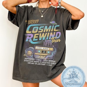 May include: A charcoal gray t-shirt featuring a Guardians of the Galaxy Cosmic Rewind Tour graphic. The design includes a cassette tape, planets, and a setlist of songs including September, Conga, Disco Inferno, Everybody Wants to Rule the World, One Way or Another, and I Ran.