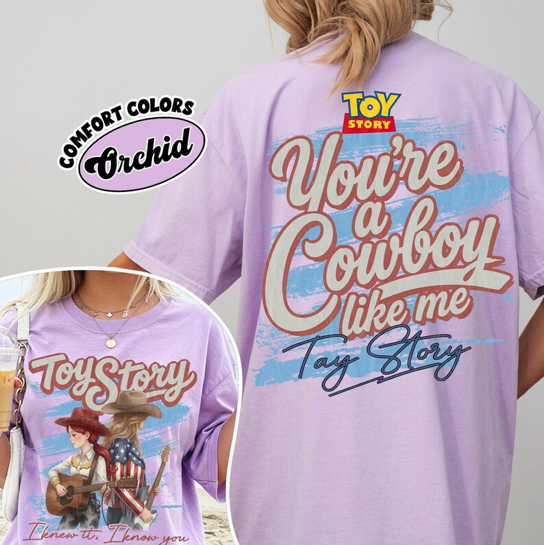 May include: A light purple short-sleeve t-shirt featuring a Toy Story graphic. The back displays the text You're a Cowboy like me and Toy Story over a blue brushstroke. The front shows two figures with guitars and the text Toy Story I knew it.