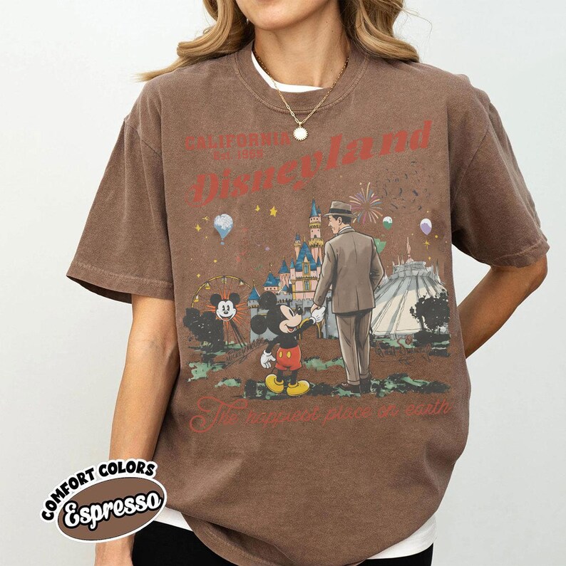Puede incluir: Camiseta color espresso con un gr&aacute;fico de Disneyland. El dise&ntilde;o incluye a Mickey Mouse, un hombre con traje, un castillo y el texto "California Disneyland Est. 1955". La camiseta tambi&eacute;n tiene las palabras "The happiest place on earth".