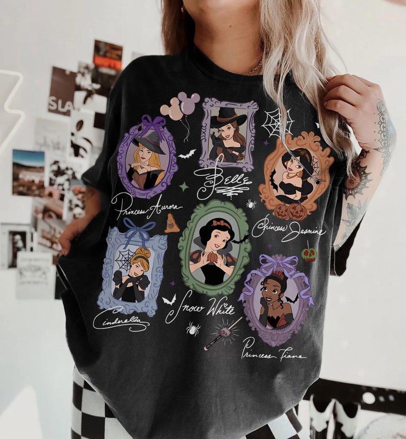 May include: Dark gray t-shirt featuring framed portraits of Disney princesses, including Aurora, Belle, Jasmine, Cinderella, Snow White, and Tiana. The shirt has a vintage, distressed look with the princesses' names in cursive.