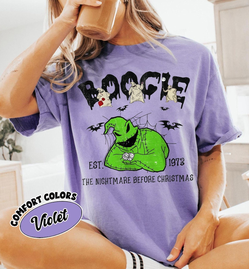 May include: A violet t-shirt featuring the word "Boogie" in a dripping font, with cartoon characters and the text "EST. 1973 THE NIGHTMARE BEFORE CHRISTMAS." A comfort colors label reads "Violet."