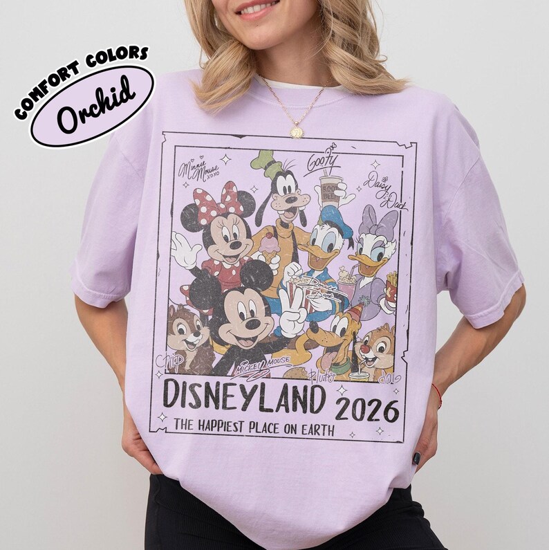 May include: Orchid-coloured t-shirt with a Disneyland 2026 graphic, featuring Mickey Mouse, Minnie Mouse, Goofy, Donald Duck, Daisy Duck, Chip, and Dale. The shirt has a vintage design and the text "The Happiest Place on Earth."