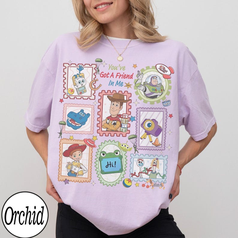 May include: A light purple short-sleeve t-shirt featuring a graphic print of various Toy Story characters inside postage stamp-style frames. The text "You've Got A Friend In Me" is printed in the centre, surrounded by illustrations of Woody, Buzz Lightyear, Jessie, and other icons.