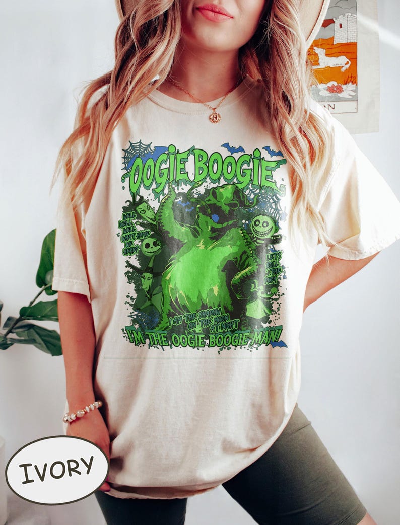 Op de afbeelding: Ivoor T-shirt met een groene afbeelding van het personage Oogie Boogie, met de tekst "Oogie Boogie" en "I'm the Oogie Boogie Man!" Het ontwerp bevat vleermuizen en andere personages uit de film.
