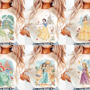 K&ouml;nnte beinhalten: Eine Sammlung von sechs cremefarbenen T-Shirts, jedes mit einer Aquarellillustration einer Prinzessin. Die Prinzessinnen sind in ihren ikonischen Kleidern mit dazugeh&ouml;riger Landschaft dargestellt. Die Shirts werden auf einer Person pr&auml;sentiert.