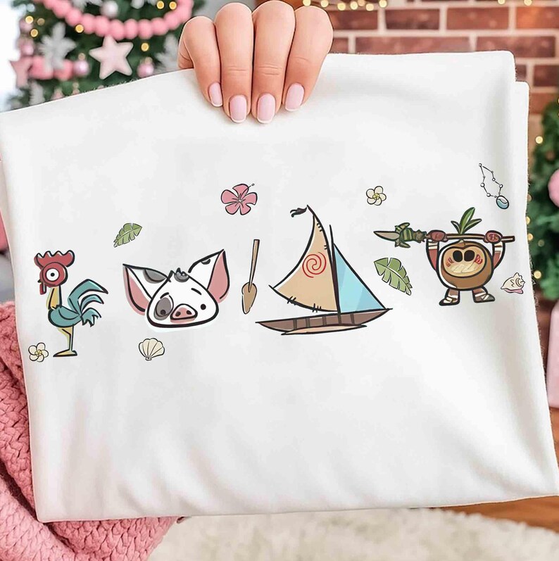 Pode incluir: Uma t-shirt branca com uma estampa gr&aacute;fica de um galo de desenho animado, um leit&atilde;o, um remo de madeira, um veleiro com uma vela em espiral e uma pequena criatura de coco segurando uma lan&ccedil;a, decorada com flores e conchas tropicais.