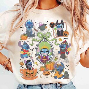 Może przedstawiać: Beżowa koszulka z motywem Halloween przedstawiającym postacie Stitcha w kostiumach. Projekt zawiera dynie, nietoperze i dekoracyjną ramkę. Koszulka ma okrągły dekolt.