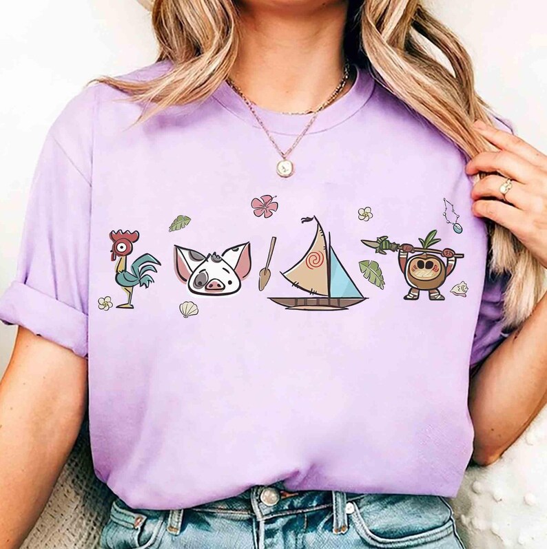 Pode incluir: Uma t-shirt roxo-claro com uma estampa gr&aacute;fica de um galo, um rosto de porco, um remo de madeira, um veleiro com uma vela em espiral e um personagem de coco segurando uma lan&ccedil;a, rodeados por pequenas flores e folhas tropicais.