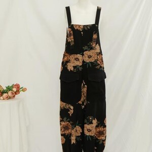 May include: Black floral print overalls with adjustable straps and pockets. The overalls have a relaxed fit and a wide leg.