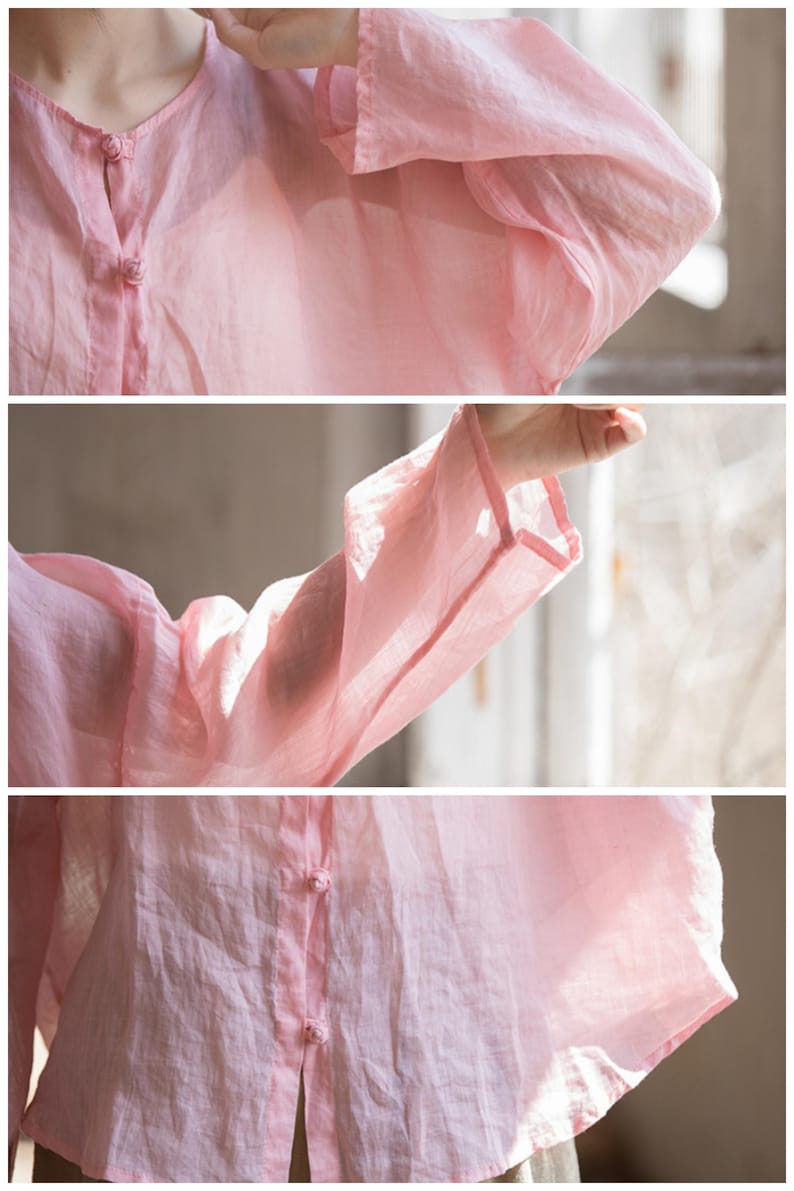 May include: A light pink, long-sleeved blouse with a V-neck and button closure. The blouse features delicate, decorative buttons and wide sleeves. The fabric appears lightweight and slightly sheer, suggesting a linen or cotton blend.