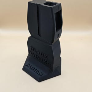 Könnte beinhalten: Ein schwarzer 3D-gedruckter Magazinhalter mit den Worten "Black Panther" und "Wakanda" auf der Vorderseite.