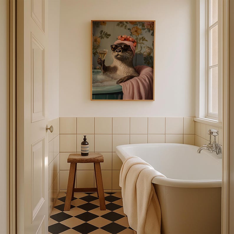 May include: A framed artwork depicts an otter in a bathtub, wearing sunglasses and a floral head wrap, holding a champagne glass. The artwork is in a bathroom setting with a wooden stool, a white bathtub, and a black and white checkered floor.