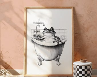 May include: Black and white framed art print of a frog relaxing in a claw-foot bathtub. The frog is drawn in detail, with the faucet and tiled wall visible in the background. The print is displayed on a pink wall.
