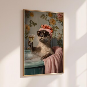 May include: A framed print depicts an otter in a bathtub, wearing sunglasses and a pink head wrap, holding a champagne glass. The otter is surrounded by bubbles and a pink towel, with a floral wallpaper background. The artwork has a whimsical and humorous theme.