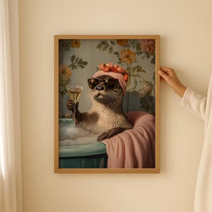 May include: A framed art print featuring an otter in a bathtub, wearing sunglasses and a floral head wrap, holding a glass of champagne. The otter is surrounded by bubbles and a pink towel, with a floral wallpaper background.