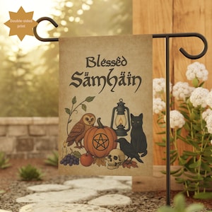 Puede incluir: Una bandera de jardín beige con las palabras "Blessed Samhain" en letras oscuras. La bandera presenta ilustraciones de una calabaza con un pentagrama, un búho, un gato negro, un cuervo, una calavera y una linterna. La bandera es de doble cara.