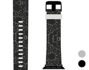 May include: Black and gray floral patterned watch band. The band features a repeating floral design in gray on a black background. The band has a black buckle and a white strap holder.