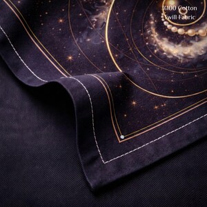 May include: A close-up of a dark navy blue fabric with a celestial design. The fabric features gold lines, stars, and a swirling galaxy pattern. The text "%100 Cotton Twill Fabric" is visible in the upper right corner.