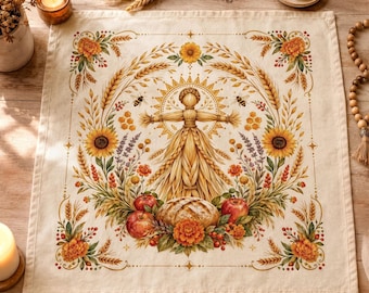 Puede incluir: Un paño de tela cuadrado de color blanco roto con una ilustración central de una muñeca de paja rodeada por un sol, espigas de trigo, girasoles, lavanda, manzanas rojas y una hogaza de pan, enmarcado por un borde floral decorativo.