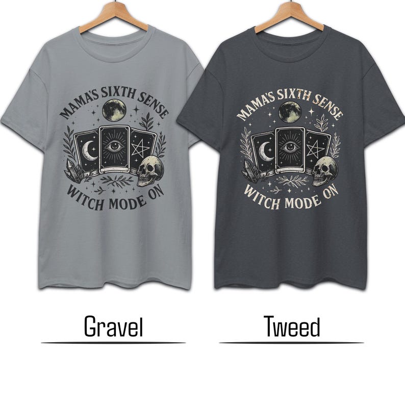 K&ouml;nnte beinhalten: Zwei kurz&auml;rmelige T-Shirts, eines grau und eines dunkelgrau, mit einem grafischen Design. Das Design zeigt Tarotkarten, einen Totenkopf, einen Mond und den Text "Mama's Sixth Sense Witch Mode On."