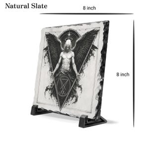 Puede incluir: Pieza decorativa de pizarra natural, de 20 cm por 20 cm, con una ilustraci&oacute;n en blanco y negro de un &aacute;ngel con grandes alas. La obra de arte incluye un dise&ntilde;o geom&eacute;trico y el texto "Natural Slate".