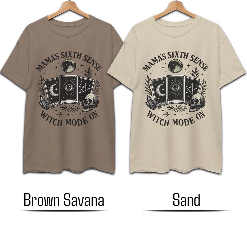 K&ouml;nnte beinhalten: Zwei kurz&auml;rmelige T-Shirts, eines braun und eines sandfarben, werden gezeigt. Jedes Shirt hat eine kreisf&ouml;rmige Grafik mit dem Text "MAMA'S SIXTH SENSE" und "WITCH MODE ON". Die Grafik enth&auml;lt Tarotkarten, einen Totenkopf und einen Mond.