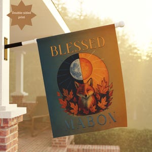 Puede incluir: Una bandera de jardín de doble cara con las palabras "BLESSED MABON" y una ilustración de zorro. El diseño presenta un zorro rodeado de hojas de otoño, con un sol y una luna. La bandera se muestra al aire libre.