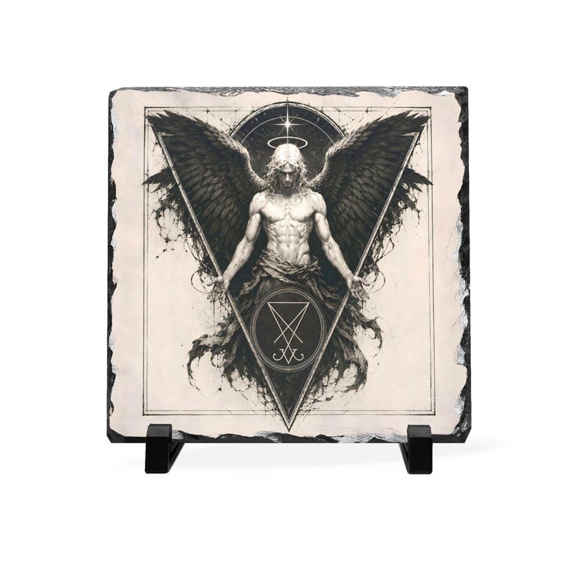 Puede incluir: Ilustraci&oacute;n en blanco y negro de un &aacute;ngel con grandes alas y un halo, impresa en una loseta de piedra cuadrada. La loseta est&aacute; soportada por un soporte negro, ideal para exhibir.