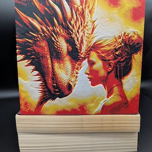 May include: A fiery red dragon with black scales and a woman with long red hair are looking at each other. The background is a fiery orange and yellow.