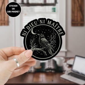 Könnte beinhalten: Schwarzer Aufkleber oder Auto-Magnet mit einem Raben auf einem Ast in einem Kreis. Die Worte "NI DIEU NI MAÎTRE" sind um den Kreis herum gedruckt. Der Hintergrund zeigt einen Sternenhimmel und einen Halbmond.
